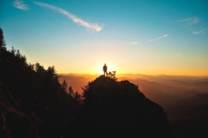 man standing on mountain sun setting